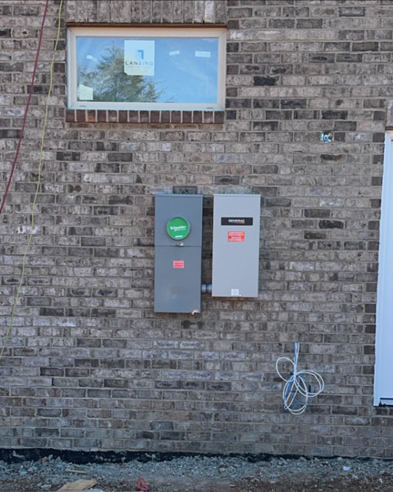 Generac and Schneider electrical panels installed on a brick exterior wall by C.M.S Electrical in Staley, NC.