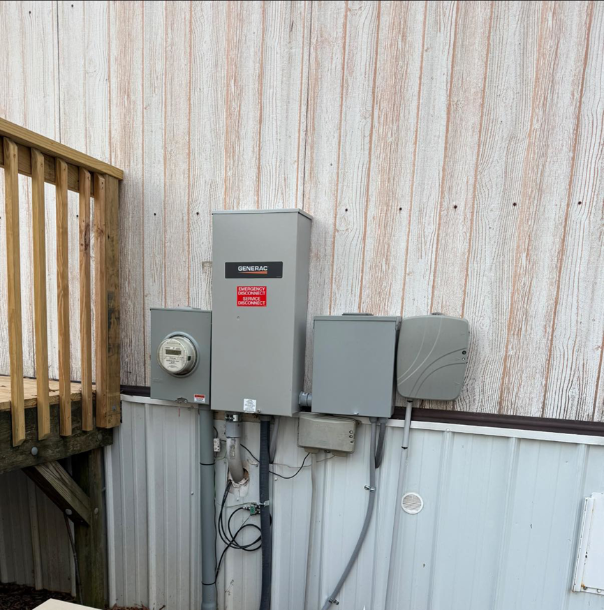 A Generac generator transfer switch and electrical meter installed on the side of a building by C.M.S Electrical in Staley, NC.