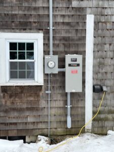 An exterior Generac generator and electrical meter installation on a home by RAD-WIRE ELECTRIC, LLC in Manchester, NH.
