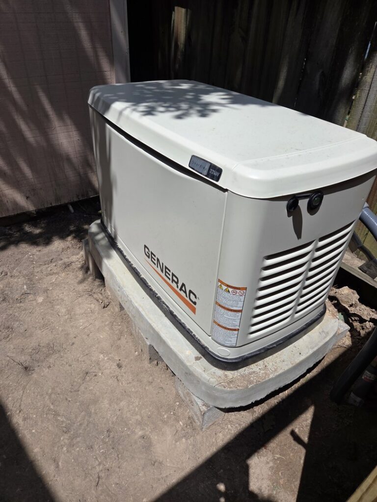 A Generac whole-home generator installed on a concrete pad next to a building by Never Without Power Generators LLC in Huffman, TX.