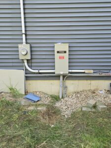 An outdoor electrical meter and a Generac generator transfer switch installed by DHJ Electric in Methuen, MA.