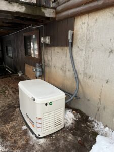 A Generac standby generator installed outside a building with electrical connections by Mountain Electric in Knoxville, TN.