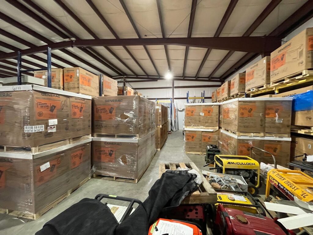 A warehouse interior showing stacks of Generac generator boxes, part of the inventory for Craig's Electrical and Generator Service in Kenner, LA.