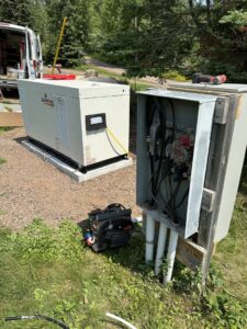 An open electrical transfer switch panel being wired next to a Generac generator by Schroeder Electric in Duluth, MN.