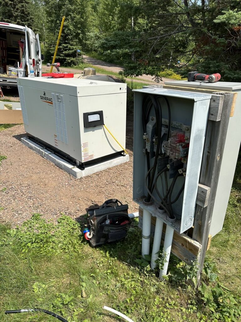 An open electrical transfer switch panel being wired next to a Generac generator by Schroeder Electric in Duluth, MN.