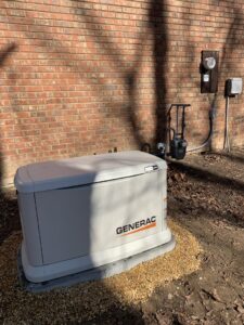 A Generac standby generator installed next to a brick house, with visible gas and electrical connections in Atlanta, GA.