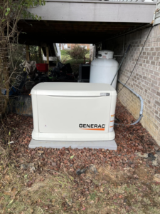 A Generac standby generator installed under a deck next to a propane tank by RJ Boyd Electric in Christiansburg, VA.