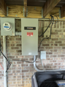 A Generac transfer switch and electrical meter installed on a brick wall under a deck by RJ Boyd Electric in Christiansburg, VA.