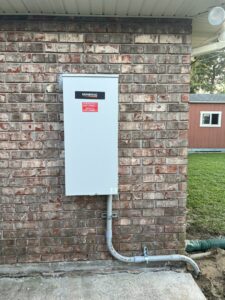 An exterior Generac transfer switch professionally installed on a brick wall with conduit by Craig's Electrical and Generator Service in Kenner, LA.