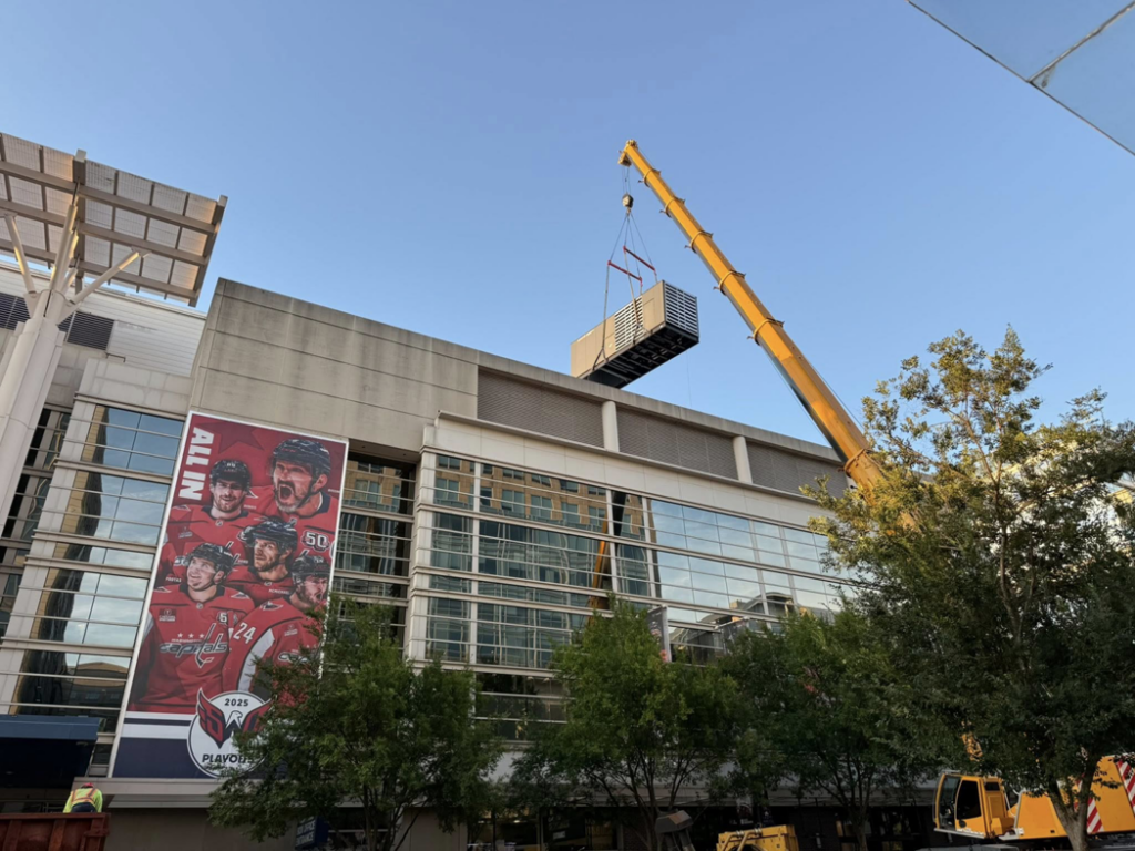 An industrial generator being carefully lifted onto a building's roof by a crane for RSL Electric LLC in York, PA.