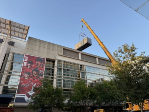 An industrial generator being carefully lifted onto a building's roof by a crane for RSL Electric LLC in York, PA.