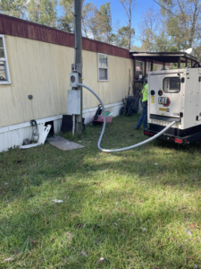 An electrician connecting a large CAT generator to a mobile home's electrical panel in Macon, GA, by Middle Georgia Electric, Inc.
