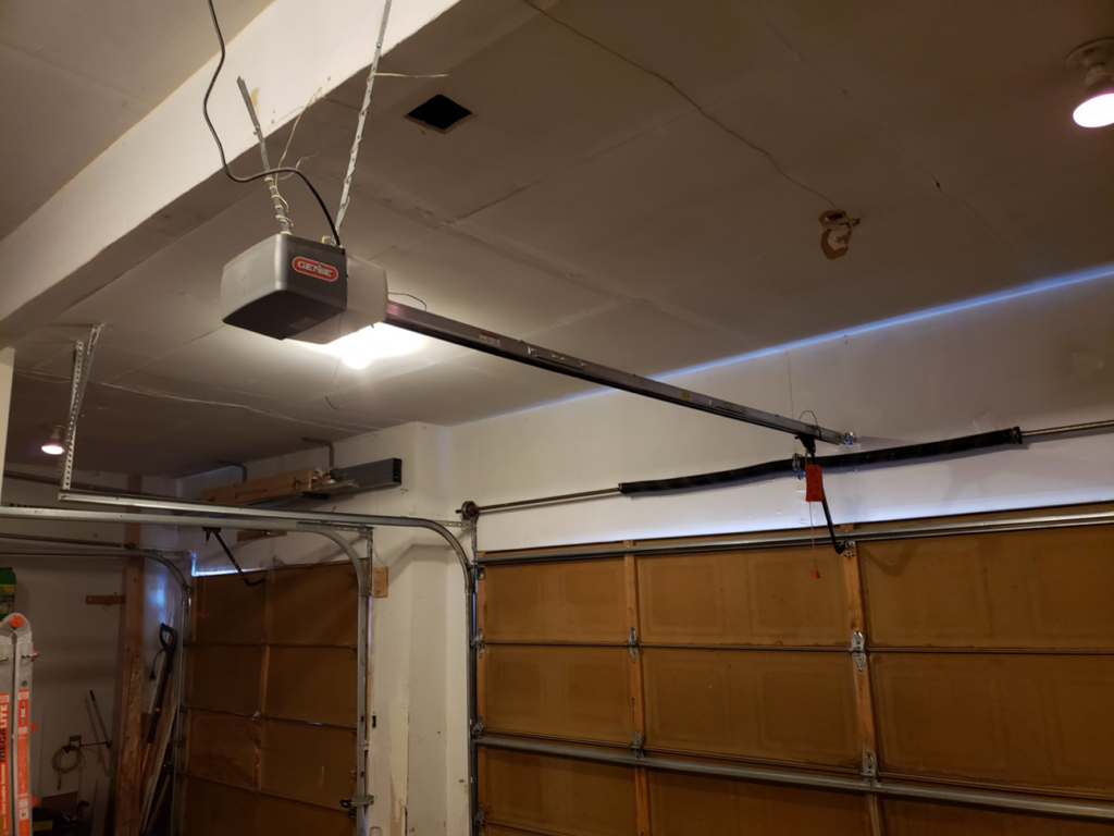 An interior view of a Genie garage door opener, tracks, and torsion springs serviced by 170 Springs LLC Garage Doors in Aurora, CO