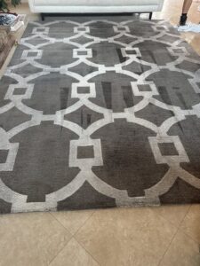 A large geometric pattern area rug showing a professionally cleaned path by Celtic Carpet Cleaner in Fort Lauderdale, FL.