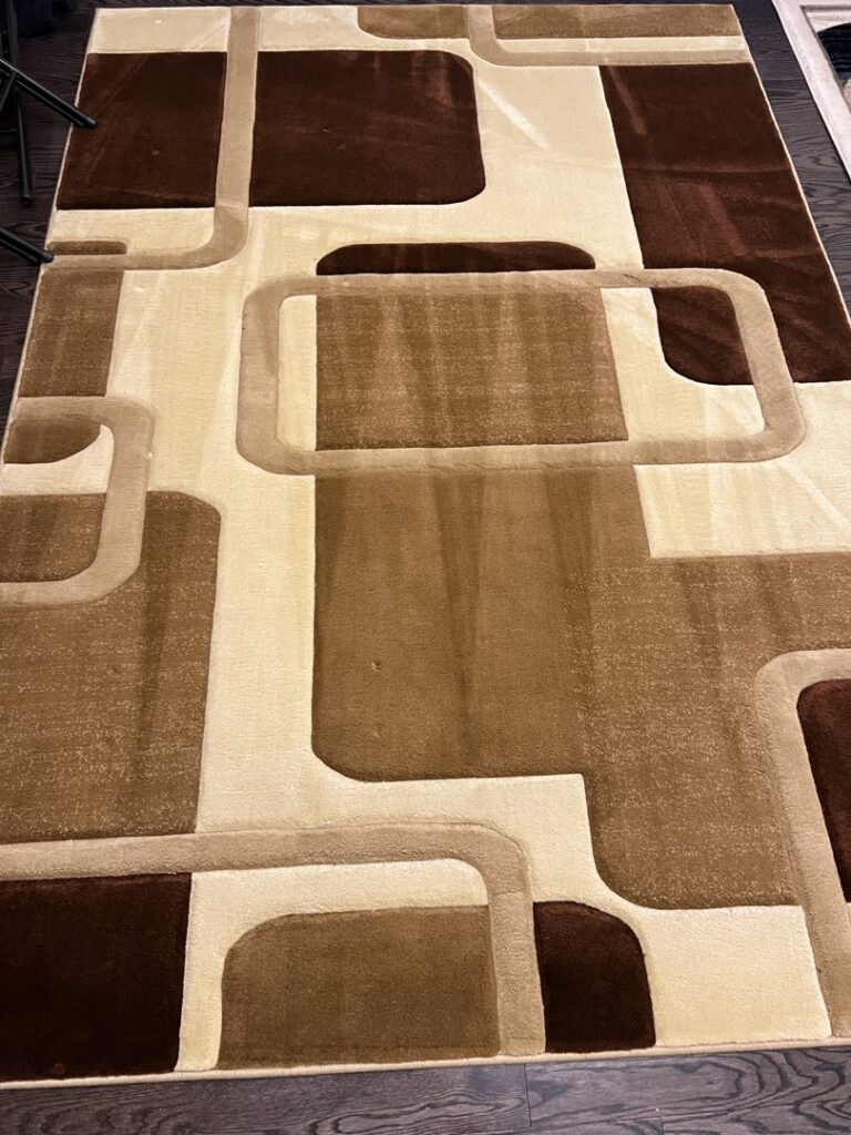 Geometric brown and beige area rug on a wooden floor, cleaned by PROlific Cleaning Services LLC in Indianapolis, IN.