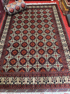 A vibrant red and orange geometric patterned carpet displayed by Mawr Store, a carpet contractor in Chaman-e-Hozori, Kabul, AF