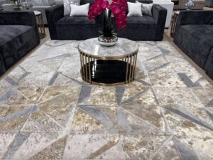 A large geometric patterned rug displayed in a showroom setting with dark sofas at Makymo in Commerce, CA