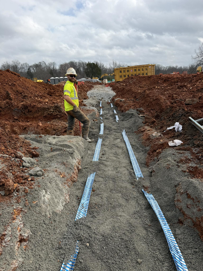 Geothermal ground loop pipes being installed in a trench by a worker from Jackson Geothermal in Mansfield, OH.