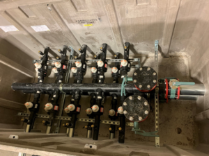 A geothermal HVAC manifold system with multiple valves and pipes installed by Environmental Loop Service in Tulsa, OK.