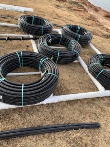 Coils of black piping laid out for a geothermal HVAC loop installation by Trinity Climate Control in Clayton, NC.
