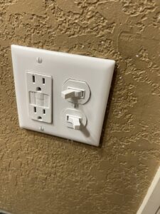 A newly installed GFCI outlet and two light switches on a textured wall by Mister Sparky Kansas City, MO.