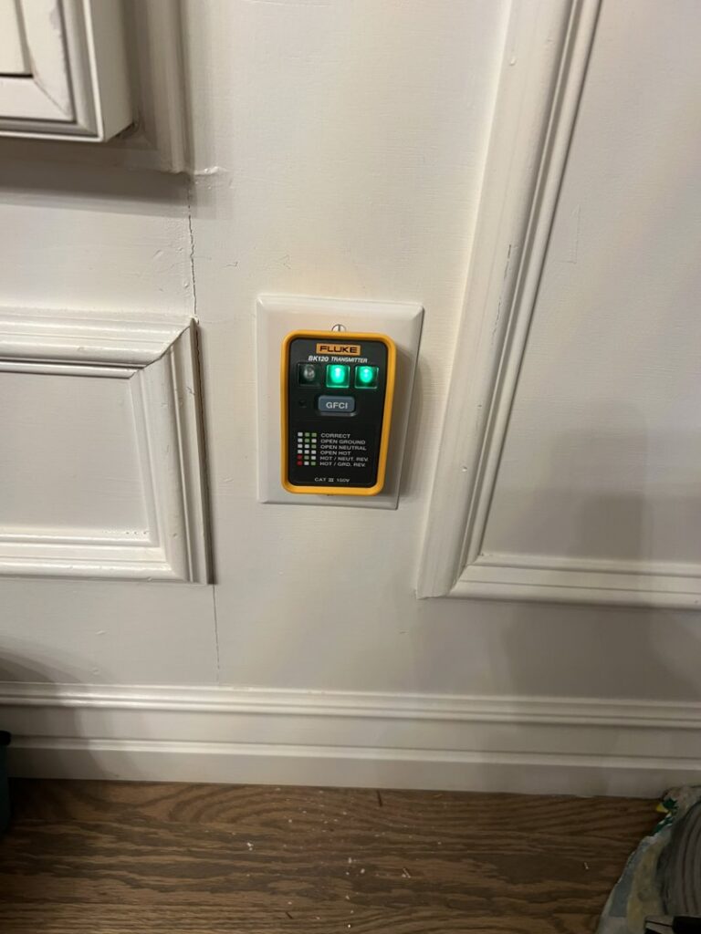 An electrician from Sparrow Electric, LLC testing a GFCI outlet with a tester in Denver, CO.