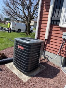 A Goodman outdoor air conditioning condenser unit installed next to a house by Grozier Heating and Air Conditioning, LLC in Allentown, PA.