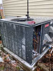 A Goodman outdoor AC unit with its panel removed, showing internal components and cleaning foam during service by Your Angel Heating And Cooling LLC in Cary, NC.