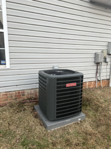 A Goodman outdoor AC unit installed next to a home with gray siding by MTZ Heating and Air Conditioning in Charlotte, NC.