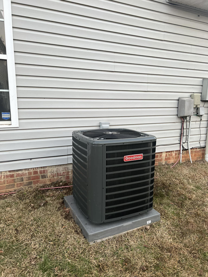 A Goodman outdoor AC unit installed next to a home with gray siding by MTZ Heating and Air Conditioning in Charlotte, NC.