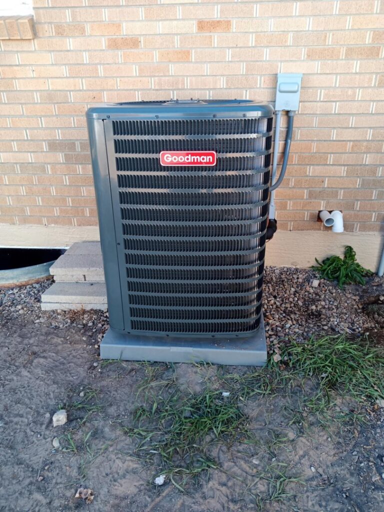 An outdoor Goodman air conditioning unit installed next to a brick home by 307 HVAC Services in Rock Springs, WY.