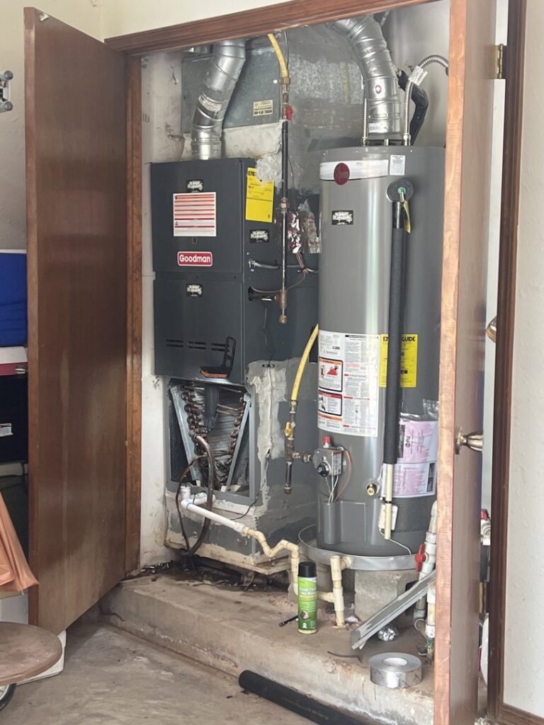 A Goodman furnace and air handler installed alongside a water heater in a utility closet by Rhino Heating and Air Conditioning LLC in Norman, OK.