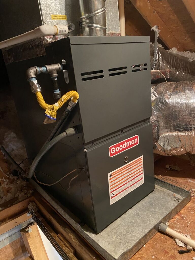 A Goodman furnace or air handler unit installed in an attic or crawl space, with gas lines and ductwork, by TJ Mechanical Services LLC in Rock Hill, SC.