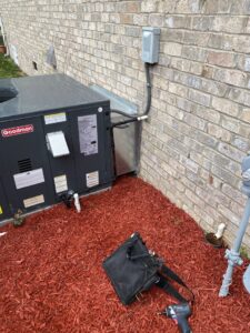 A Goodman outdoor HVAC unit recently installed next to a brick wall, with tools nearby, by Luciano's Air Services in Durham, NC.