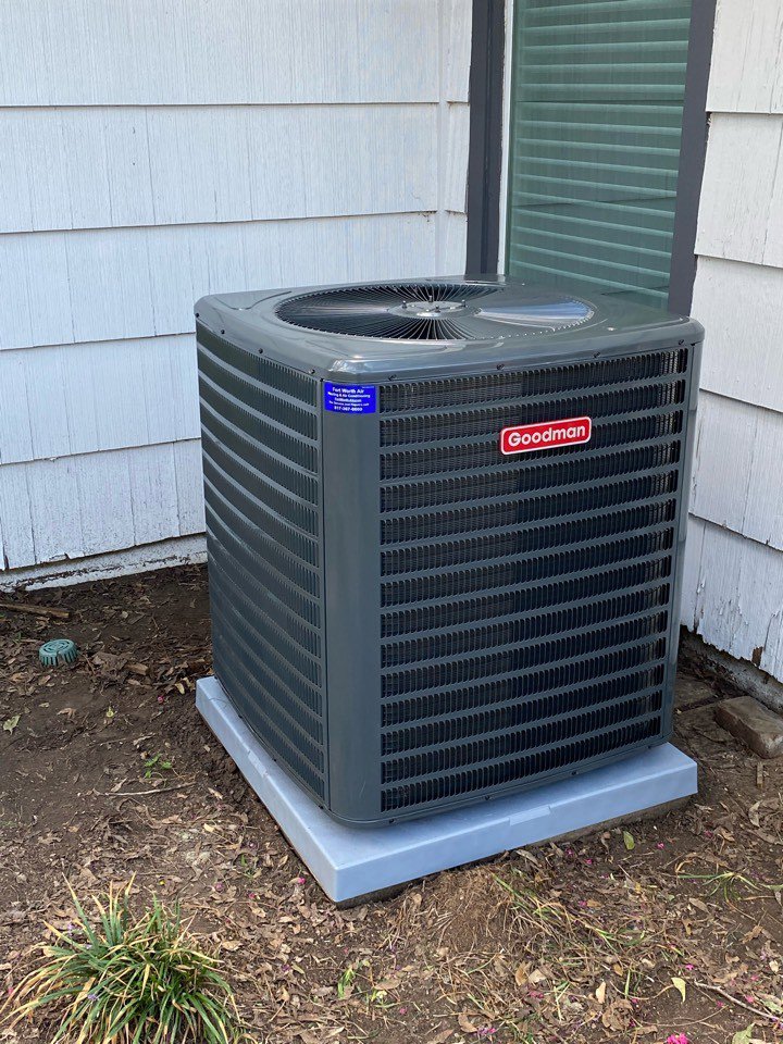 A Goodman outdoor AC unit installed next to a house by Fort Worth Air Conditioning Co. Inc. in Fort Worth, TX.