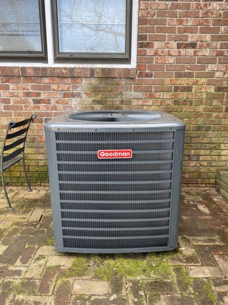 A Goodman outdoor AC unit installed on a brick patio, maintained by TJ Mechanical Services LLC in Rock Hill, SC.