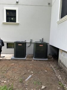 Two Goodman brand outdoor air conditioning units installed next to a modern home by Express Home Services LLC in Las Vegas, NV.