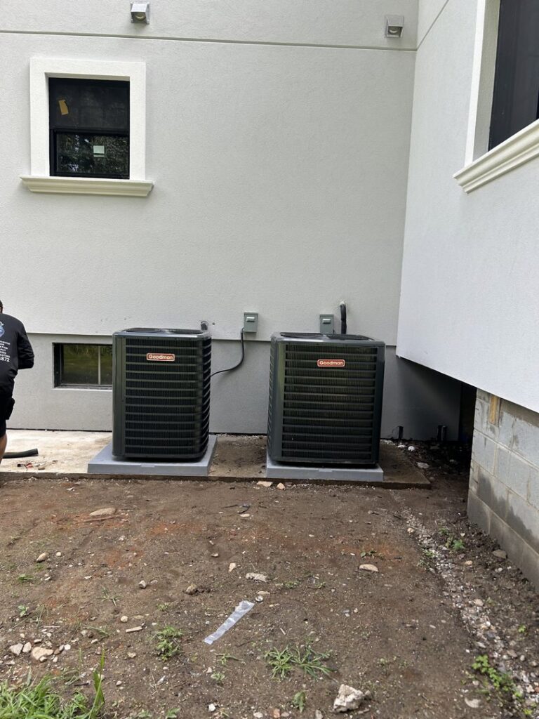 Two Goodman brand outdoor air conditioning units installed next to a modern home by Express Home Services LLC in Las Vegas, NV.