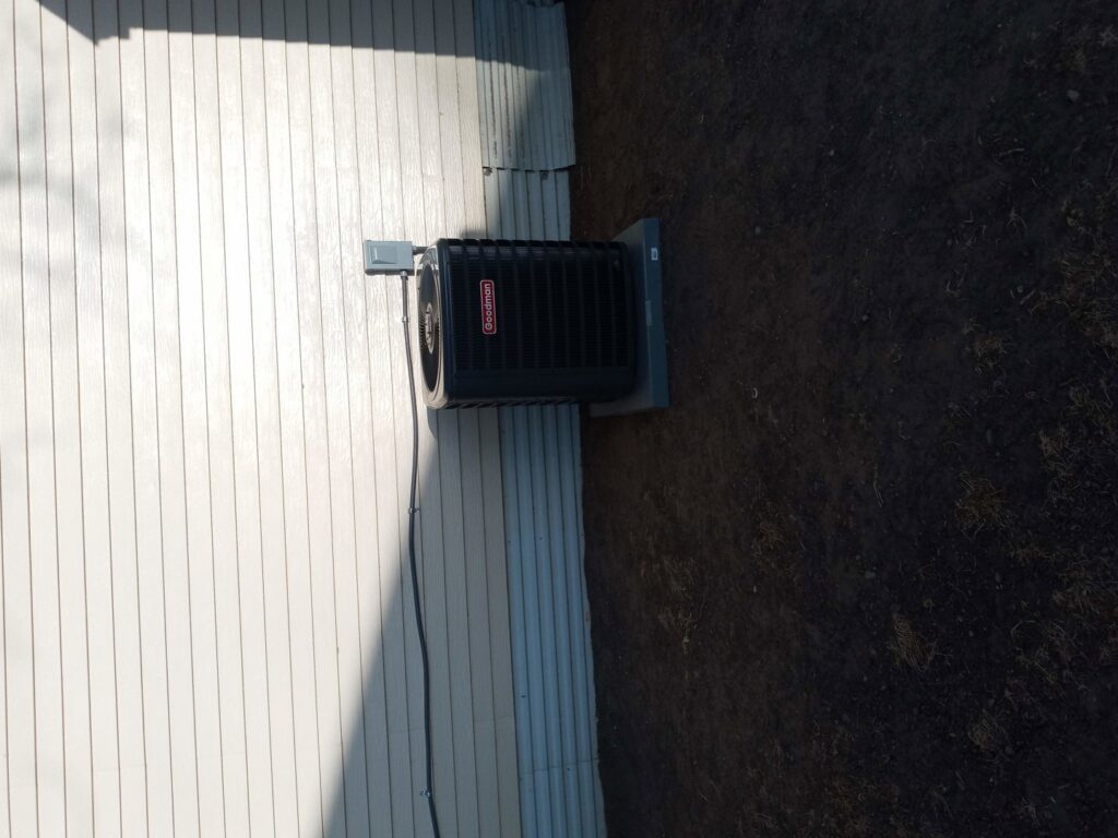 A Goodman brand outdoor air conditioning condenser unit installed, showcasing HVAC services by Jones Heating and Refrigeration in Dickinson, ND.