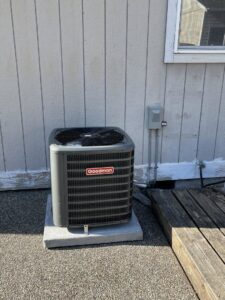 A Goodman brand outdoor HVAC condenser unit installed next to a home by Best Heat & Air in Tacoma, WA.