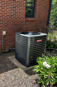 A Goodman outdoor HVAC condenser unit installed next to a brick home by G & N Heating and Cooling in Huntsville, AL.