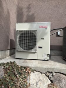 A newly installed Goodman outdoor HVAC unit (air conditioner or heat pump) by Authority Heating & Cooling in Orem, UT.