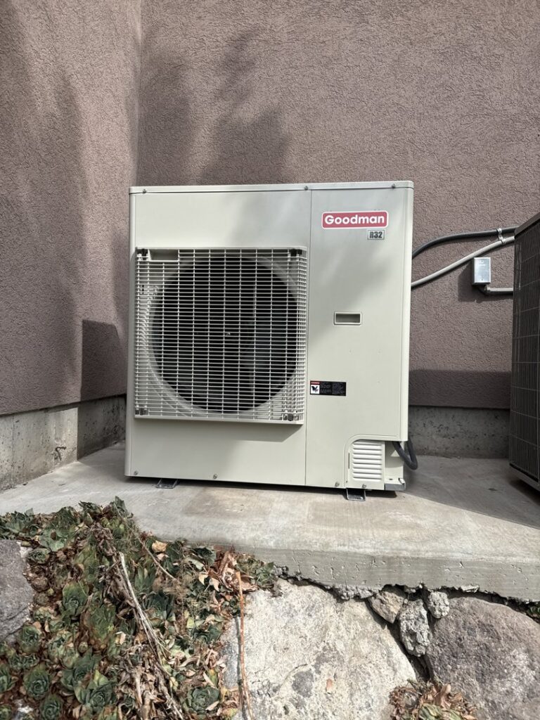 A newly installed Goodman outdoor HVAC unit (air conditioner or heat pump) by Authority Heating & Cooling in Orem, UT.