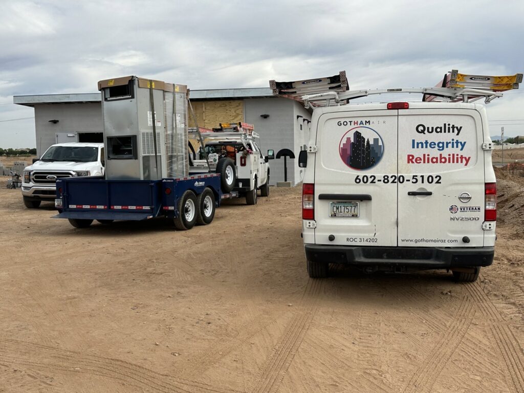 A Gotham Air LLC service van and trailer with HVAC equipment on a job site in Glendale, AZ.
