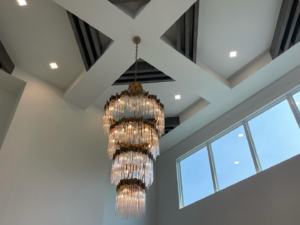 A grand chandelier and recessed ceiling lights installed in a high-ceiling room by Outlaw Electric in Tulsa, OK.