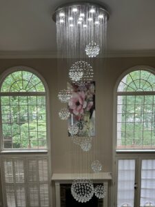 Grand crystal chandelier installation in a high-ceiling entryway by Perfection Lighting, Design, and Installations in Atlanta, GA.