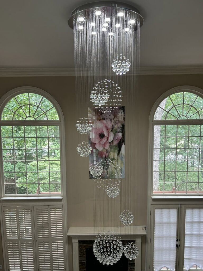 Grand crystal chandelier installation in a high-ceiling entryway by Perfection Lighting, Design, and Installations in Atlanta, GA.