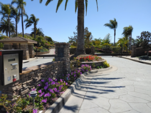 A grand entrance with stone pillars, an intercom, and decorative metal gates by Automated Entry Systems Inc in Escondido, CA.