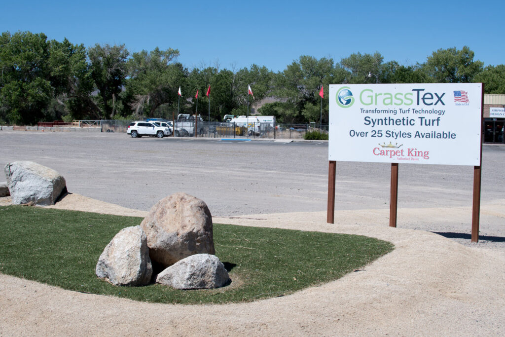 An outdoor sign advertising GrassTex synthetic turf, featuring the Carpet King Interiors / Abbey Carpet & Floor logo in Fernley, NV.
