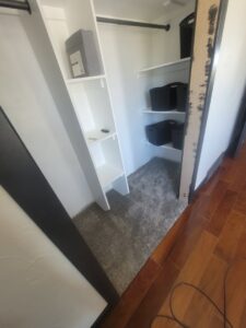 A closet with newly installed gray carpet, transitioning to wood-look flooring in the hallway by Taylor Carpets & Flooring in Provo, UT